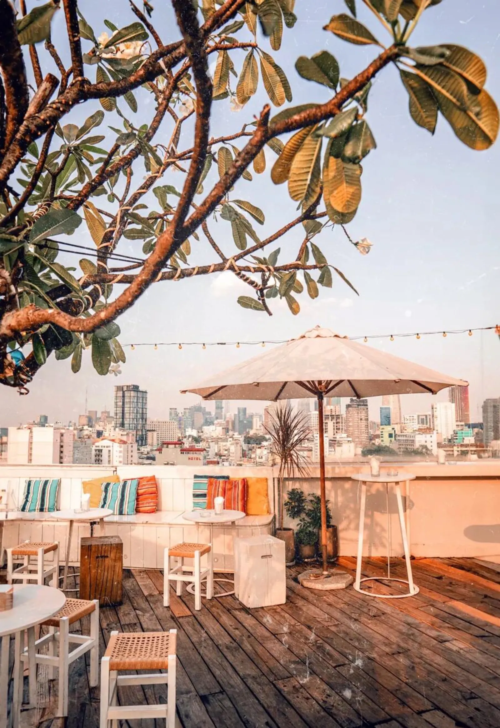 Banana Mama Rooftop Bar ban ngày với gối nhiều màu, dù trắng và view trung tâm Sài Gòn
