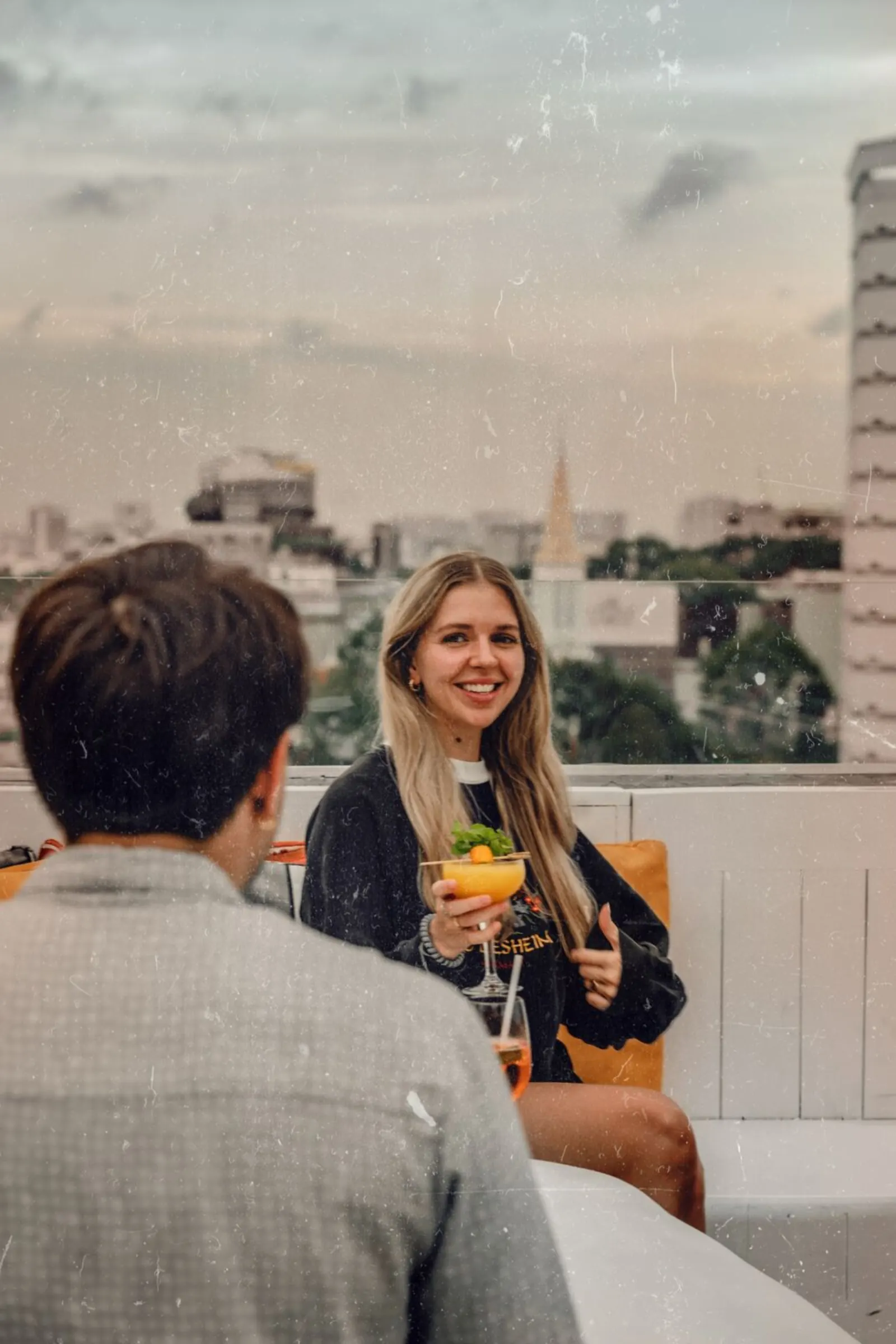Khách nước ngoài cười nói và nâng ly cocktail tại Banana Mama Rooftop Bar lúc hoàng hôn Sài Gòn