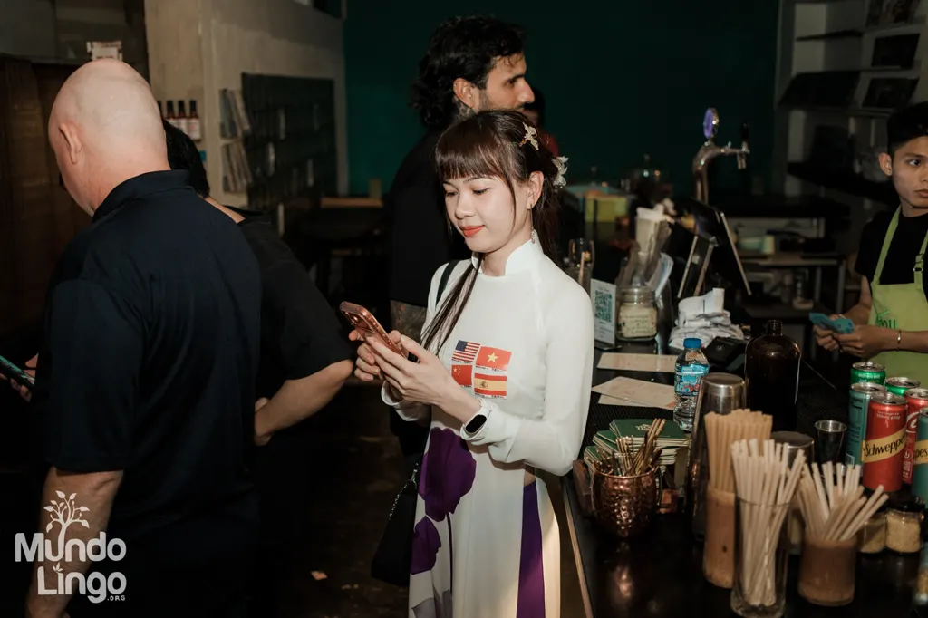 Cô gái mặc áo dài trắng dán sticker cờ Mỹ, Việt Nam, Trung Quốc, Tây Ban Nha tại quầy bar Mundo Lingo Saigon