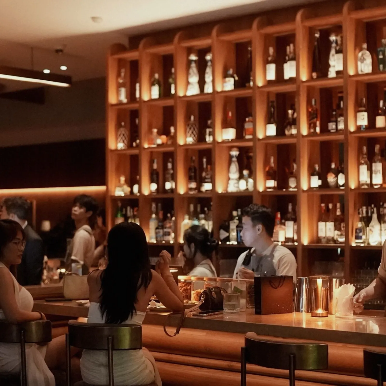 Quầy bar Papaya Papa với kệ rượu vang và whisky cao cấp được chiếu sáng ấm áp